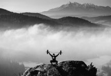 Este fanático del fitness levanta pesas en la cima de una montaña Este fanático del fitness levanta pesas en la cima de una montaña