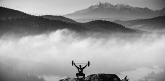 Este fanático del fitness levanta pesas en la cima de una montaña Este fanático del fitness levanta pesas en la cima de una montaña